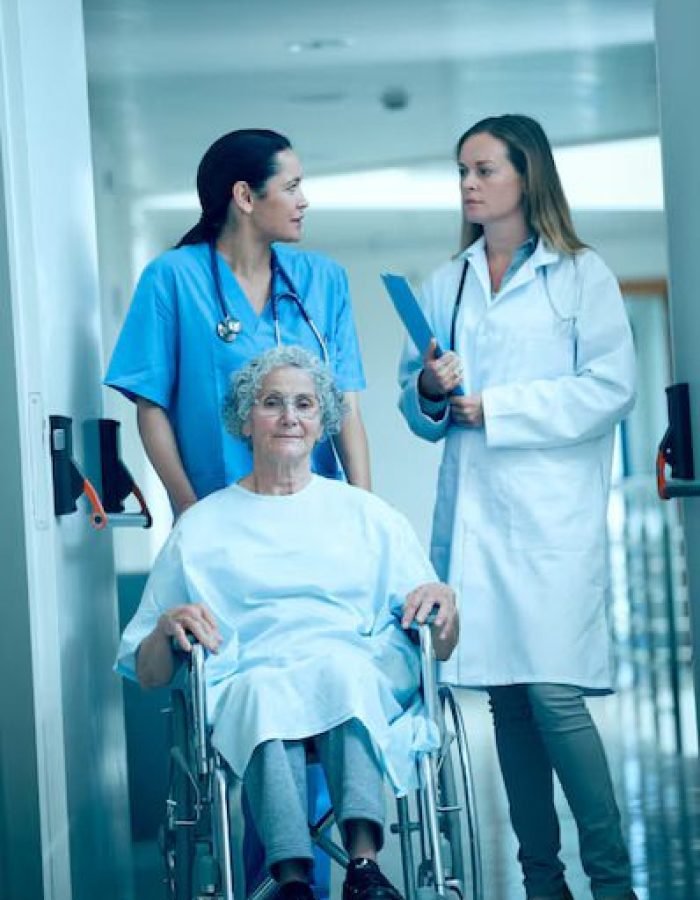 nurse-wheeling-senior-patient-patient-hallway_13339-288459